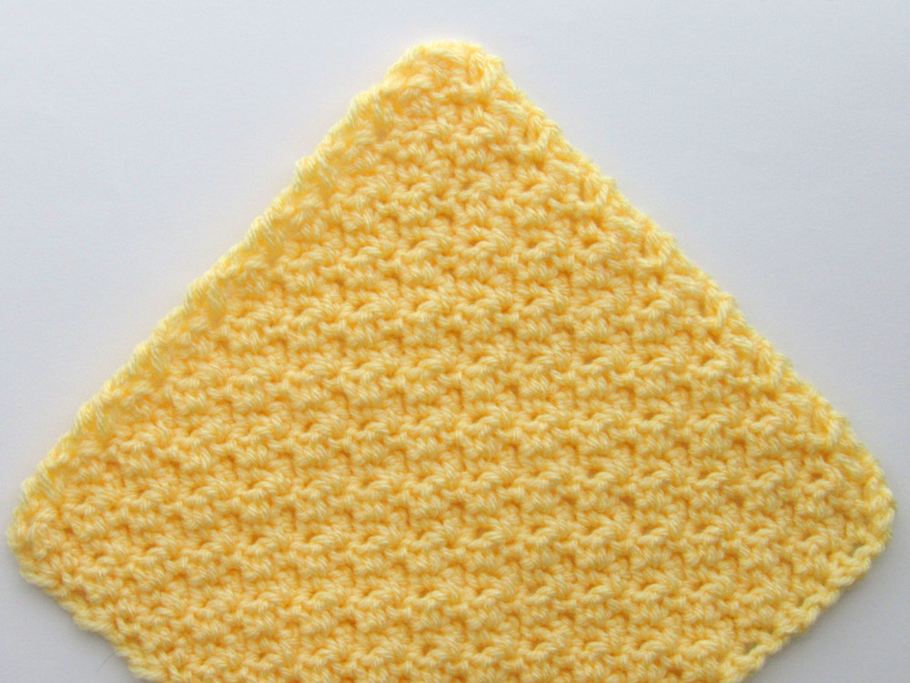 a view of 3/4th of a yellow c2c lemon peel stitch crochet square, positioned so that one corner is on the top, one is on the left, and one is on the right.